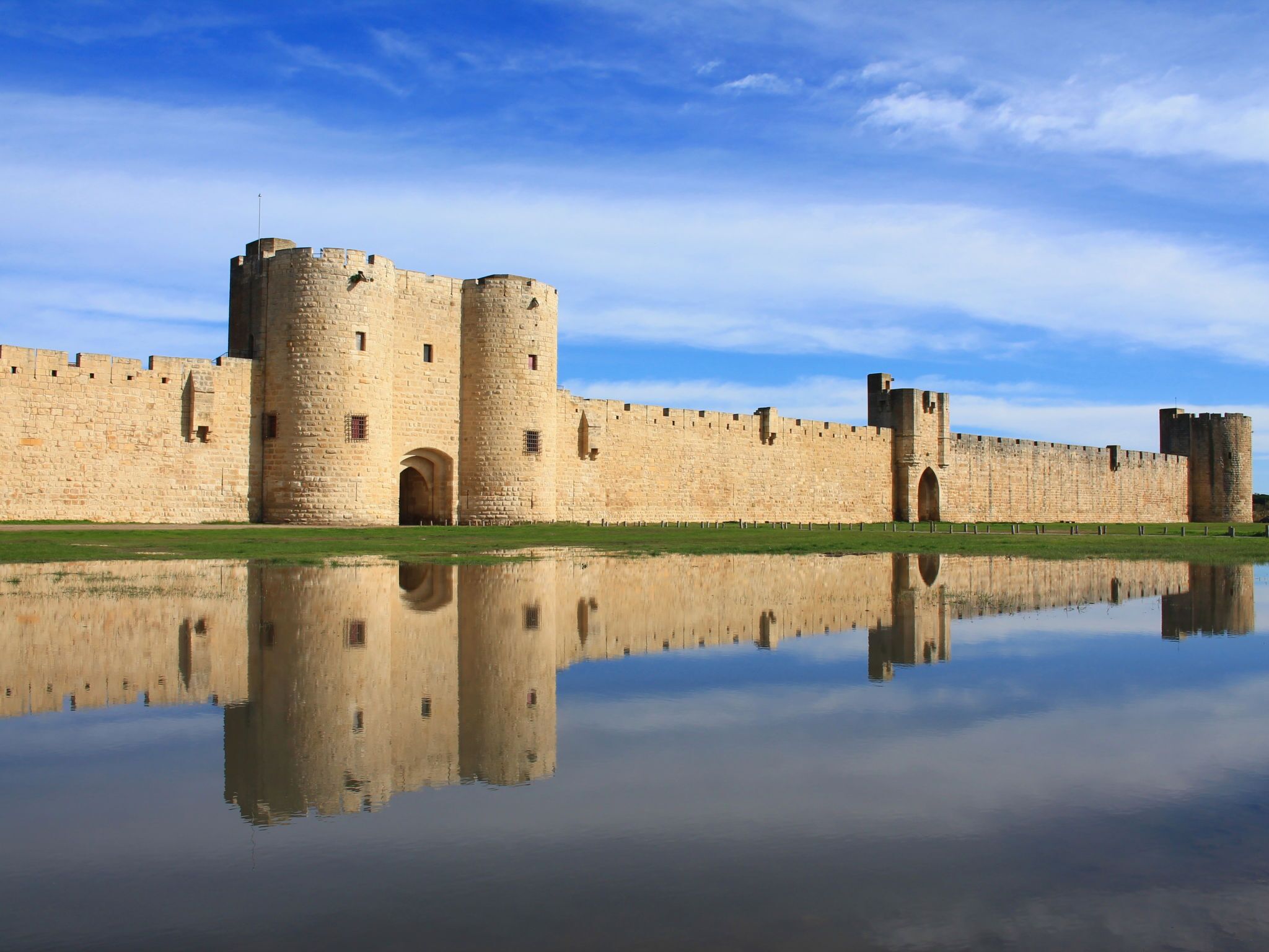 A historic stone castle with a moat and reflective water surface.