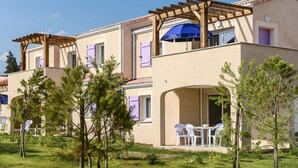 Un edificio a due piani con una pergola, posti a sedere all'aperto e un patio coperto.