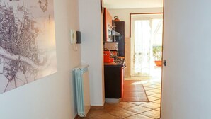 A narrow hallway with a radiator, a map on the wall, and a kitchen area with a stove and cabinets. - Samuele by Interhome (Civezza)