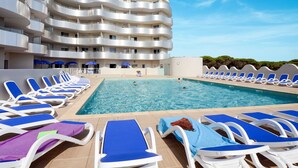 A hotel with a swimming pool surrounded by lounge chairs and umbrellas. - Odalys Référence Le Lotus Blanc by Interhome (Le Barcarès)