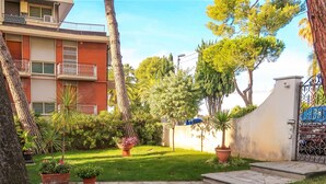 Une cour avec un chemin en pierre, des plantes en pot et un bâtiment doté de balcons.