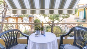 A terrace with a table set for two, a bottle of champagne, and a small potted plant. - Imperatrice by Interhome (Sanremo)