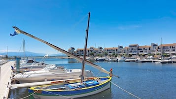 Un puerto deportivo con barcos amarrados, un muelle de madera y edificios al fondo.