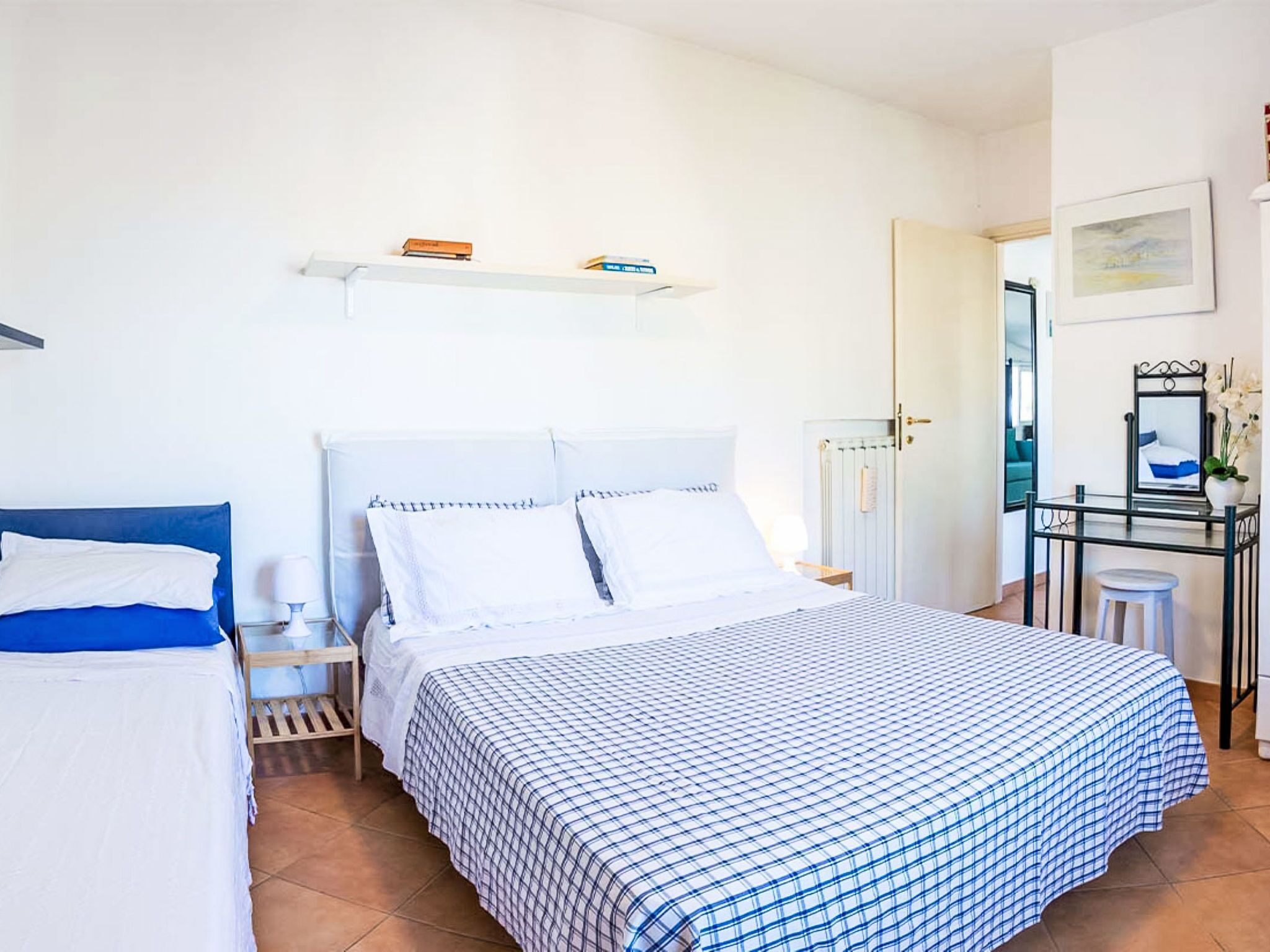 A bedroom with a bed, bedside tables, a desk, and a chair.