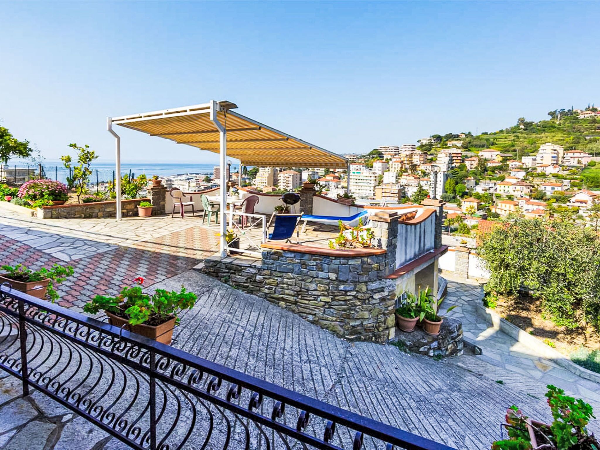 Una terrazza sul tetto con una pergola, posti a sedere e piante in vaso.