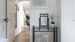 Une chambre d’hôtel avec un lit, une table de chevet avec un miroir, une plante en pot et une chaise.