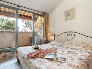 A bedroom with a bed, a window, a lamp, and a framed picture on the wall.