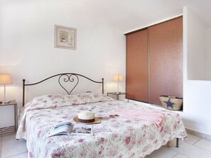 A bedroom with a bed, two bedside tables, a nightstand, a window with a view, and a wall-mounted picture.