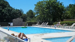 A swimming pool with lounge chairs and a person lying on one of the chairs.