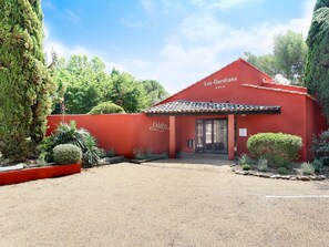 A red building with a tiled roof and a sign reading "Les Gardians."