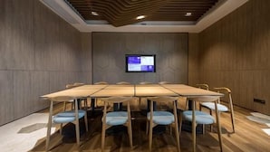 A conference room with a long table, chairs, a mounted screen, and wooden panel walls. - Mercure Qidong Downtown (QIDONG)