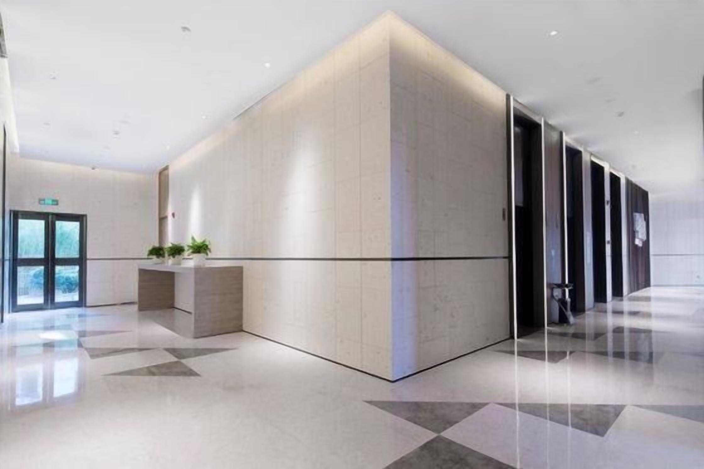 Un vestíbulo moderno con una recepción, una pared grande con un diseño geométrico y un piso limpio y pulido.