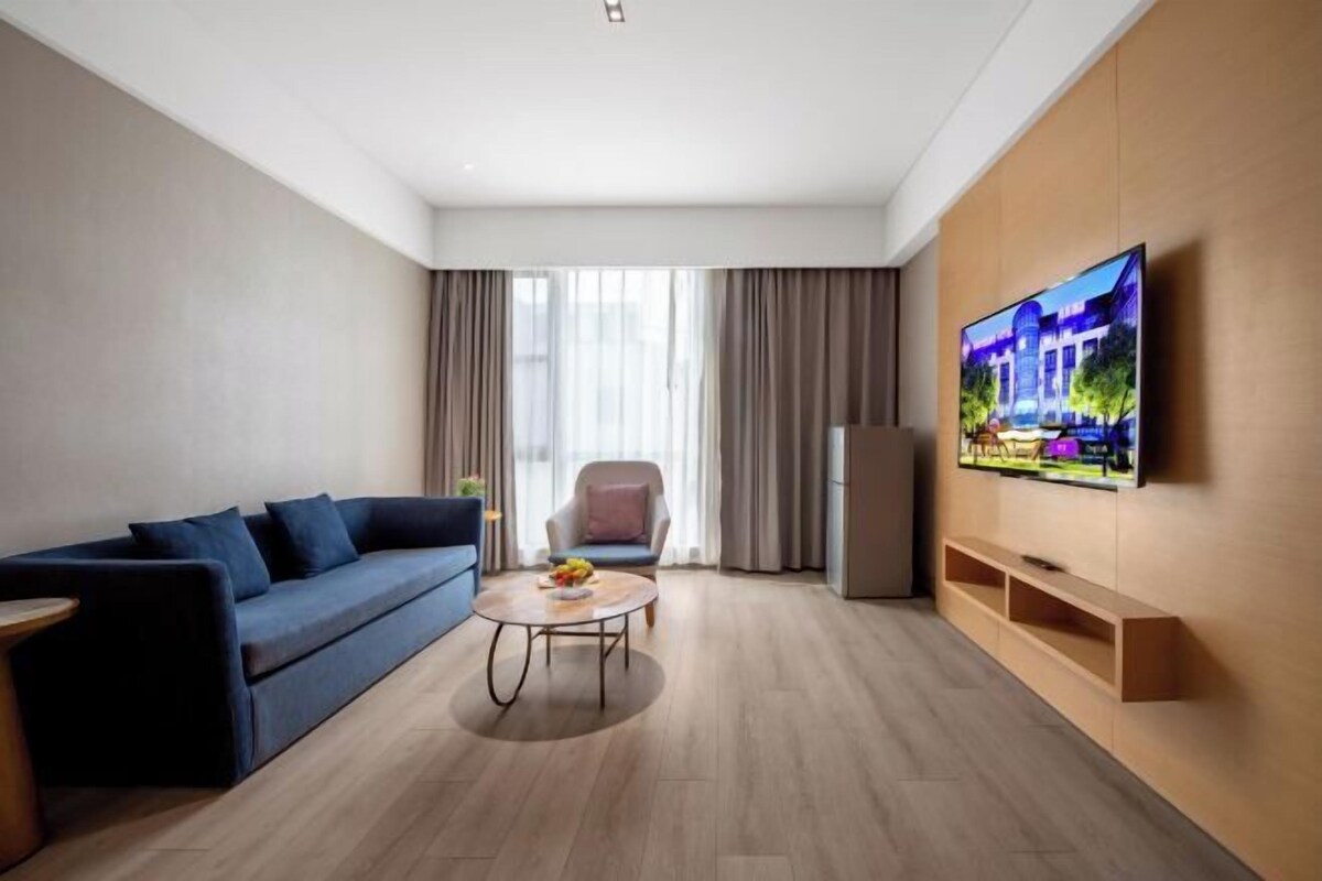 A modern living room with a sofa, a coffee table, a TV, and a chair.