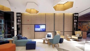 A modern lobby with a seating area, a digital display, and a unique ceiling design. - Mercure Qidong Downtown (QIDONG)