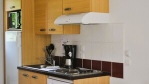 Una cocina compacta con armarios de madera, lavavajillas integrado, cafetera y microondas.