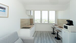 Eine kleine Küche mit Fenster, einer Couch und einer Mikrowelle.