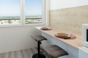 Eine Küche mit Fensterblick, einem Barhocker und einem Essbereich mit Teller und Besteck.