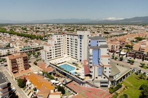 Un hôtel de grande hauteur, avec de nombreux étages, une piscine sur le toit et un paysage urbain environnant.