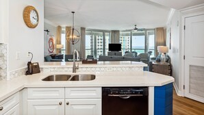 A modern kitchen with a built-in dishwasher, a double sink, and a large window offering a view of the city.
