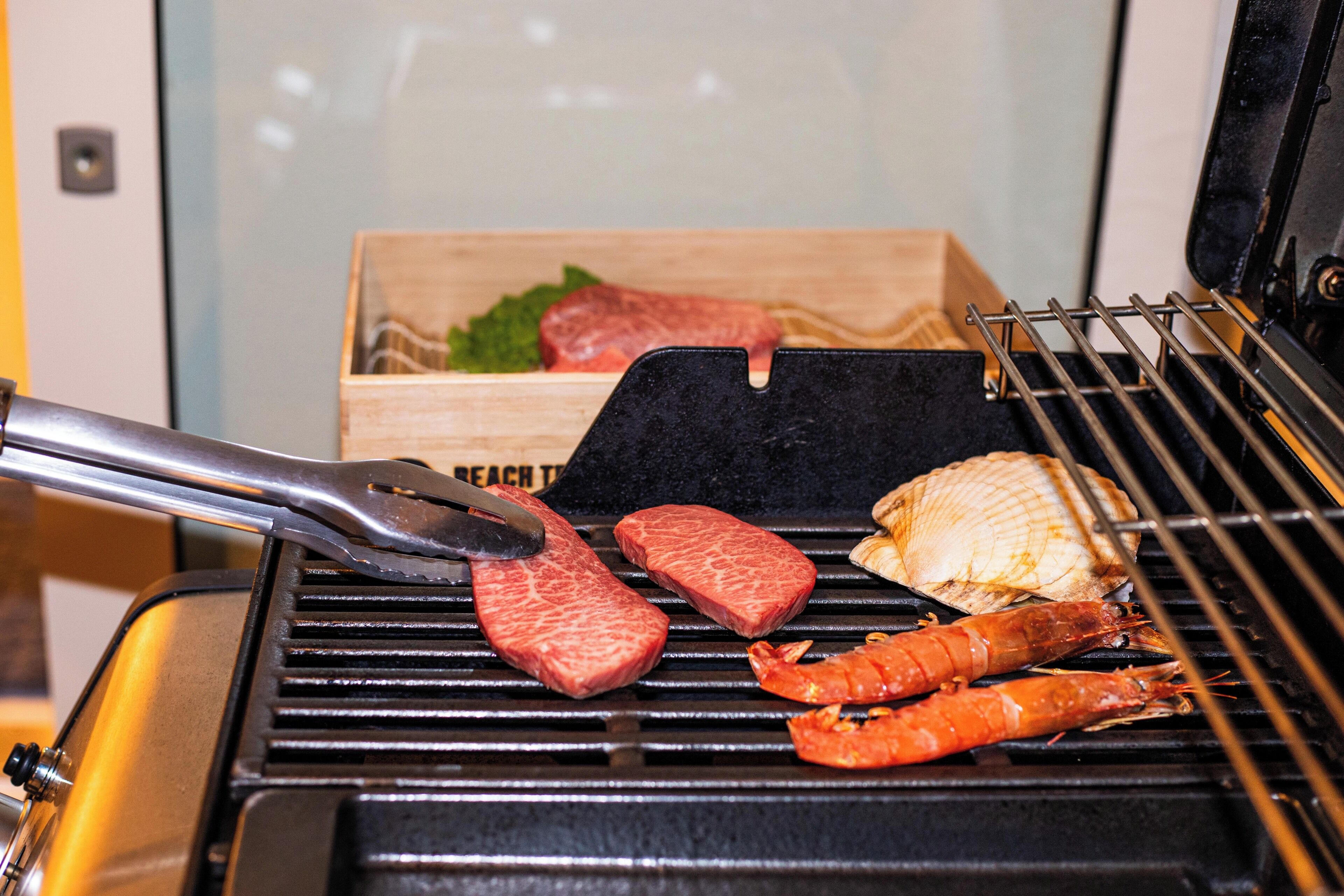 A grill with various meats and seafood being cooked.