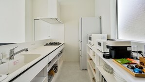Cozinha compacta com armários brancos, fogão a gás, micro-ondas e geladeira.