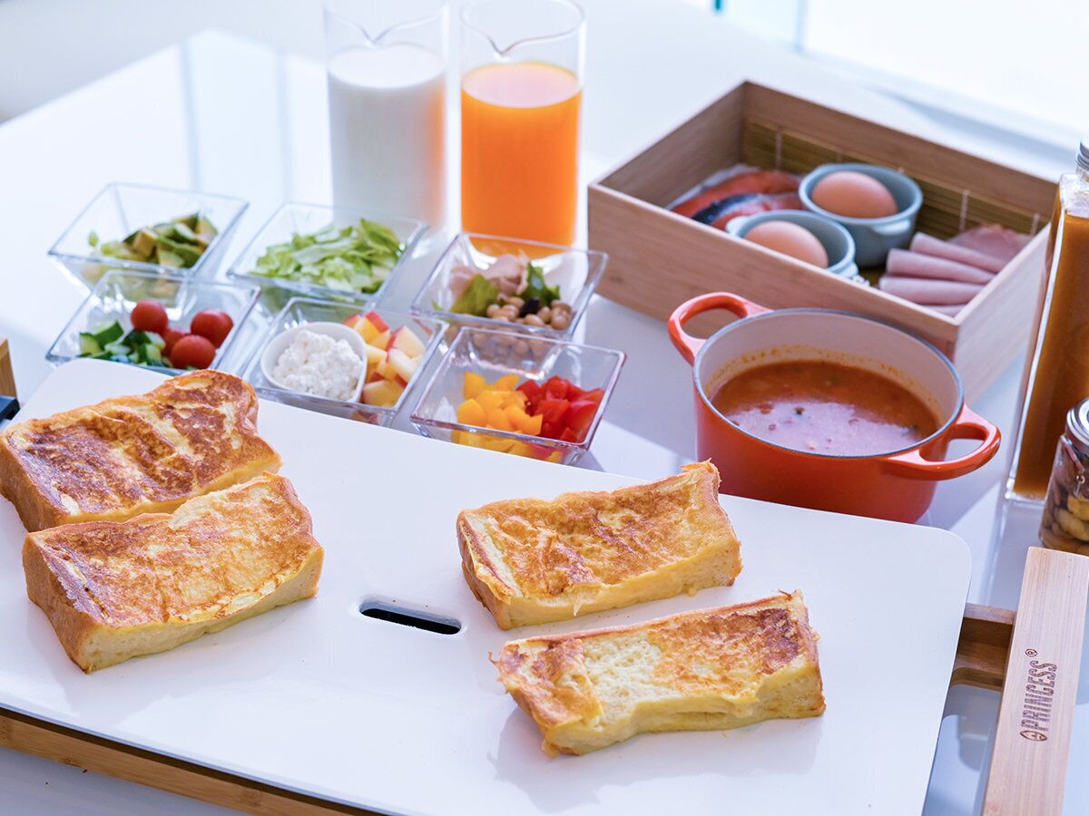 Bandeja de desayuno con tostadas, fruta y una cazuela de sopa.