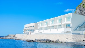 Um edifício moderno e branco com várias varandas com vista para o mar.