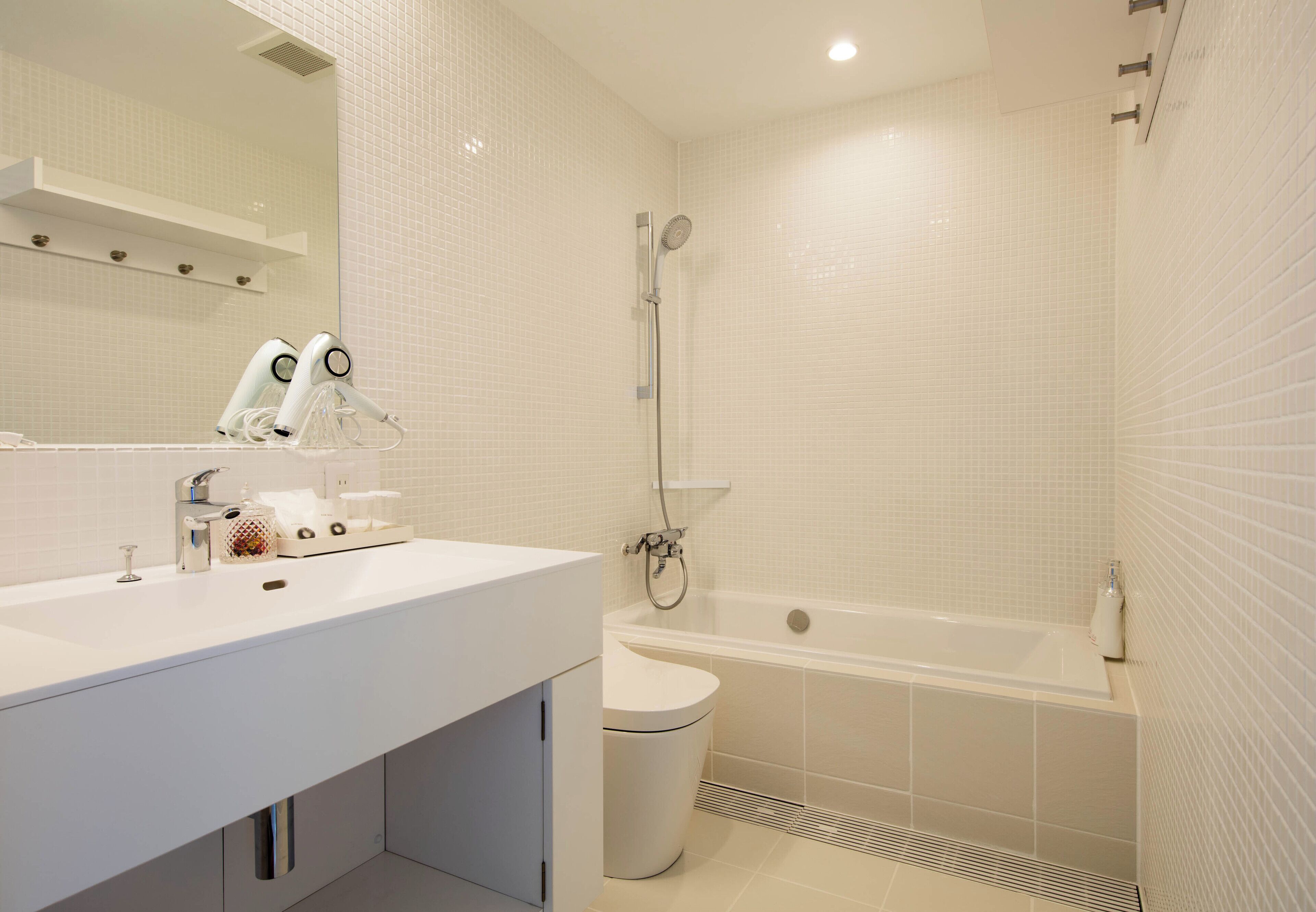 Un baño moderno con lavamanos blanco, inodoro, bañera y ducha.