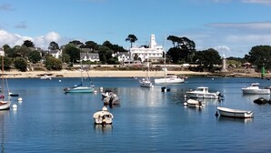 Un pueblo costero con un faro, barcos y casas a lo largo de la costa.