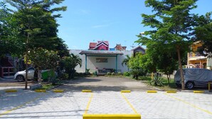 A parking lot with yellow lines and a building in the background. - Homestay Cendana Candi-1 (Kudus)