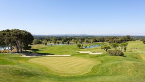Golfkenttä, jolta avautuu esteetön näkymä maisemaan, mukaan lukien puut, vesistöt ja kauempana kohoavat kukkulat.