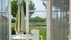 A conservatory with a table, chairs, and a view of a golf course.