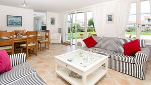 Una sala de estar luminosa con comedor, un sofá a rayas y una mesa de centro de vidrio.