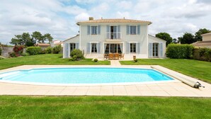 Una amplia casa de dos pisos con una piscina al frente.