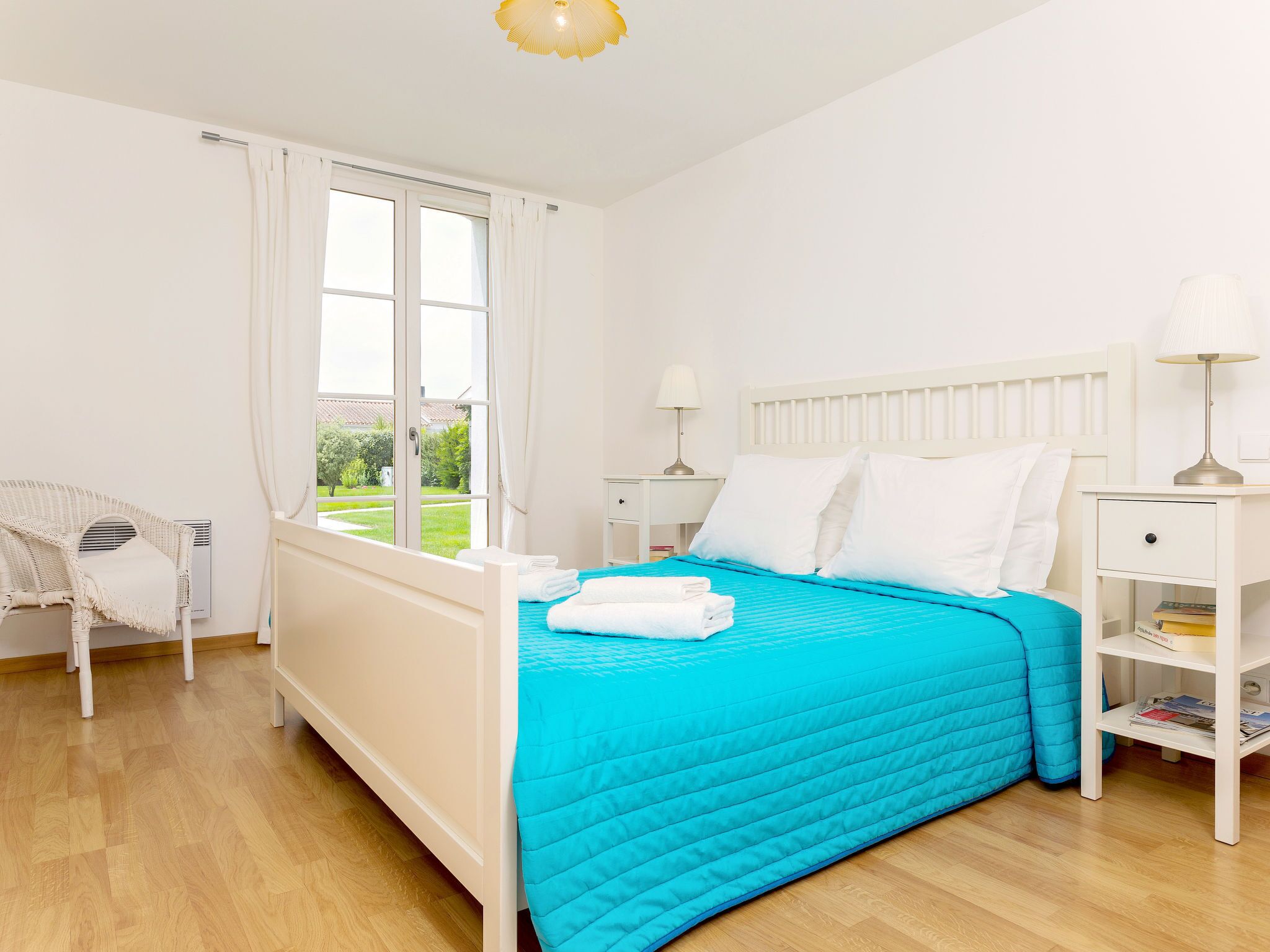 A bedroom with a bed, a chair, a window, and a nightstand with a lamp.