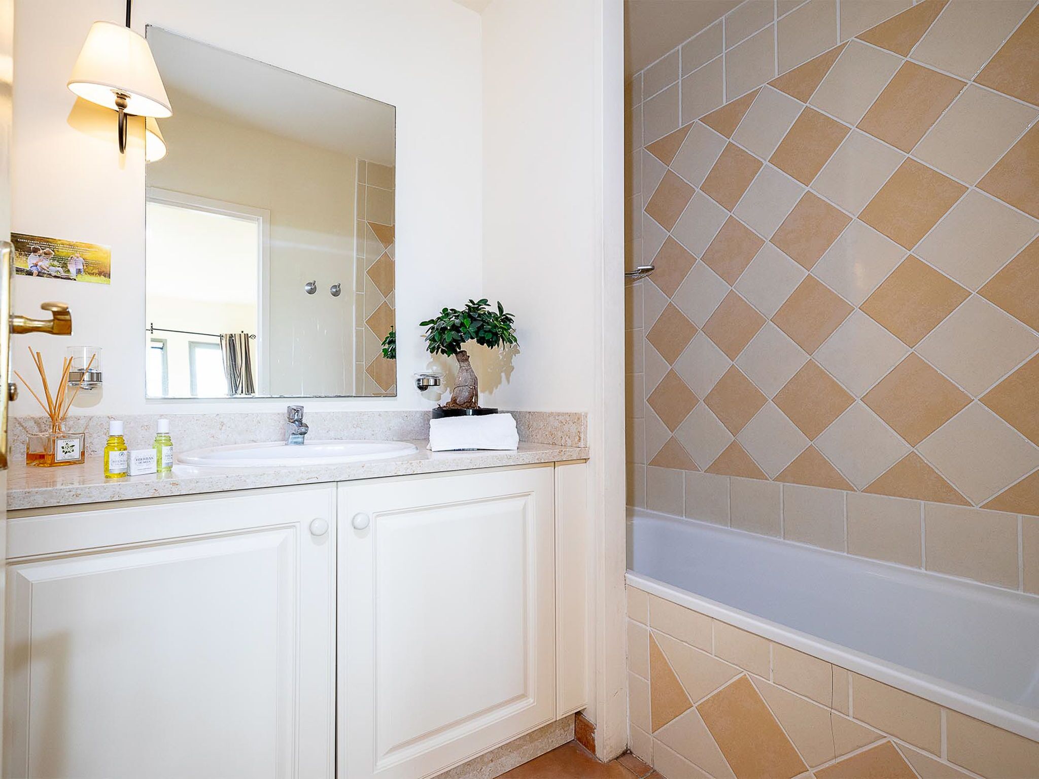 Un baño con tocador blanco, espejo, lavamanos y bañera.