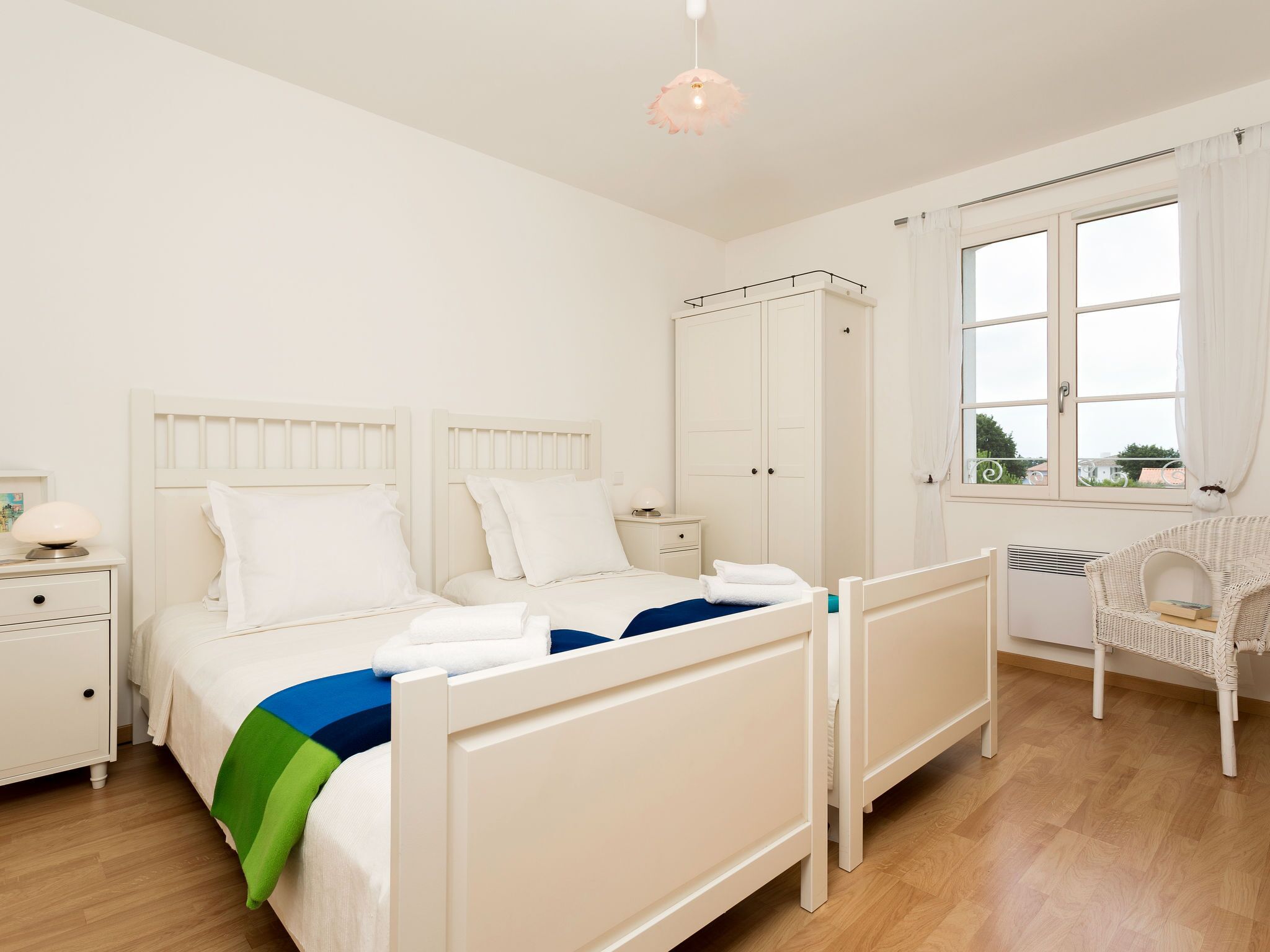 Een slaapkamer met een bed, nachtkastjes, een kledingkast, een bureau en een raam met gordijnen.