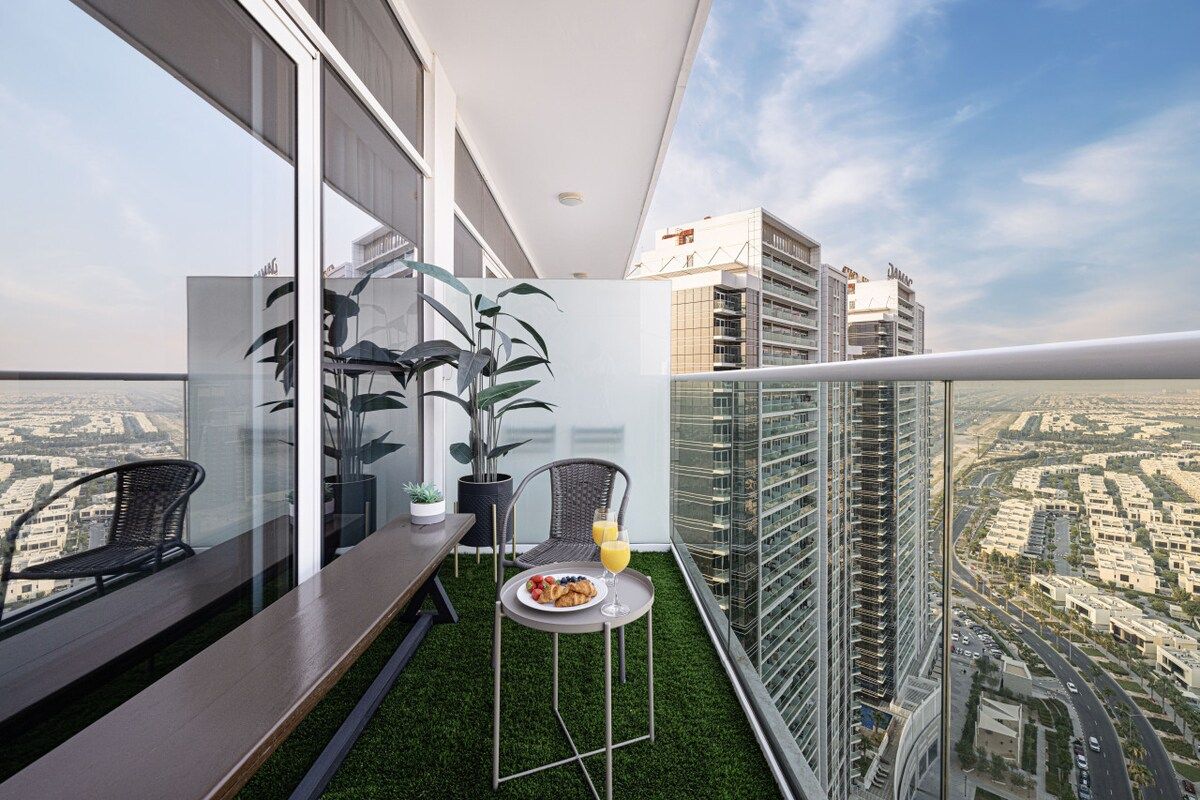A balcony with a dining table, chairs, and potted plants.