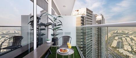 A balcony with a dining table, chairs, and potted plants.