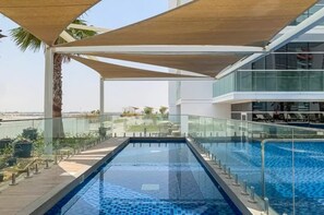 A modern hotel with a rooftop infinity pool, glass railings, and a view of the cityscape.