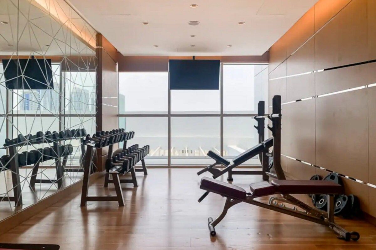 Una palestra con attrezzi per allenamento, ampie finestre e vista sulla città.
