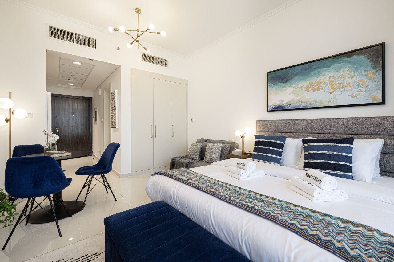 Een moderne hotelkamer met een groot bed, een bureau met stoelen en een schilderij aan de muur.