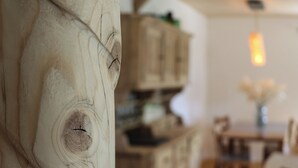 Ein Holztisch mit Stühlen, eine Holzkommode und eine Hängeleuchte in einem Raum mit Holzboden.