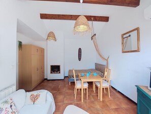 A cozy living room with a sofa, a dining table with chairs, a wooden cabinet, and a hanging light fixture.