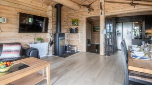 Een houten interieur met een open haard, eethoek en keuken.
