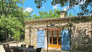 Un edificio de piedra con techo de tejas, una puerta de madera y una mesa con sillas en el exterior.