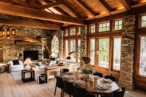 A rustic interior with stone walls, wooden beams, a fireplace, and a dining area set for a meal.