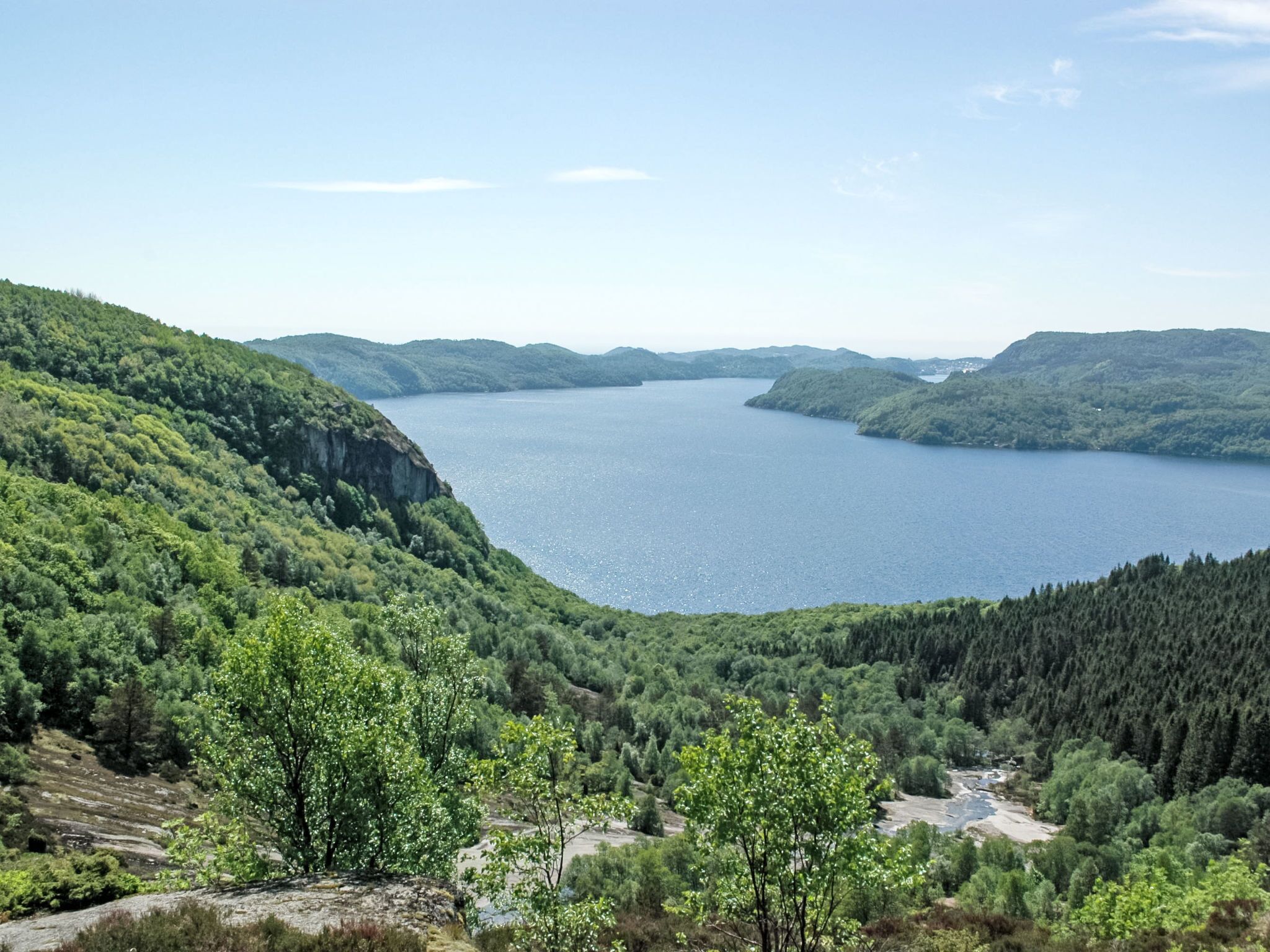 A panoramic view of a lake surrounded by forested hills.