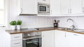 Een moderne keuken met witte kastjes, roestvrijstalen apparatuur en een houten aanrecht.