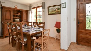 A dining area with a wooden table set for four, surrounded by chairs. There is a cabinet with glassware and a painting on the wall. - A qui sian ben by Interhome (L'isle sur la Sorgue)